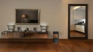 A room with a brown hardwood floor, a tall mirror and picture frame on the wall