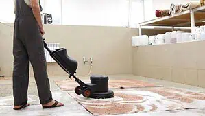 A man is washing area rugs using a professional rug shampooer.