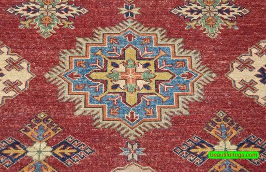 Hand knotted oriental carpet with red color in center and beige in borders, the design is Kazak.