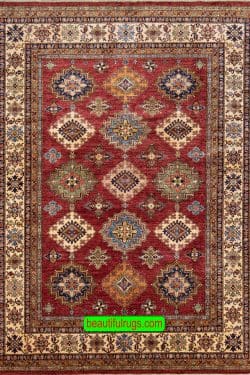 Hand knotted oriental carpet with red color in center and beige in borders, the design is Kazak.