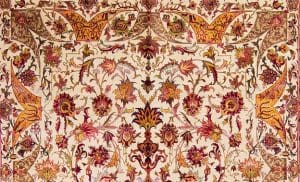 A portion of a hand knotted Persian Isfahan rug made of wool and silk in beige, red, green, pink, brown and gold colors.