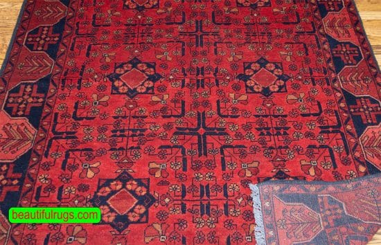 Handmade Afghan Kunduz rug in red and black color made of wool. Size is 4.10x6.7.