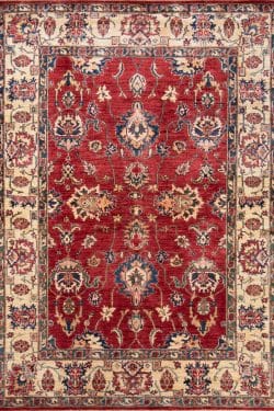 A floral-geometric handmade wool Kazak style rug in red and beige colors. Size 6x9.