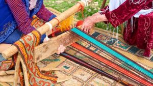 Two ladies are trying to set up a horizontal loom to weave a new rug.