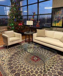 Image of Persian Isfahan rug a glass coffee table on floor, living room designed with beige furniture and Christmas tree.