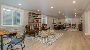living room with oak hardwood floor, checkered rugs on the floor with table, chairs and bookshelf.