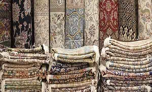Folded and stacked rugs in front of the rolled Persian rugs placed against the wall. Folded and stacked rugs in front of the rolled Persian rugs placed against the wall.