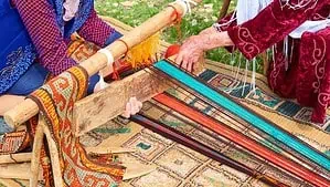 Two ladies are trying to set up a horizontal loom to weave a new rug.