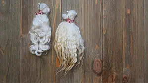 Two small wool skeins hanged on a brown color wooden wall.