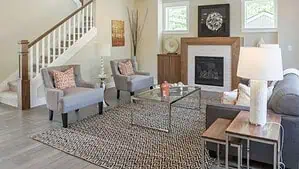 A small living room with fireplace, gray furniture, glass-top coffee table set on a brown and beige contemporary rug A small living room with fireplace, gray furniture, glass-top coffee table set on a brown and beige contemporary rug